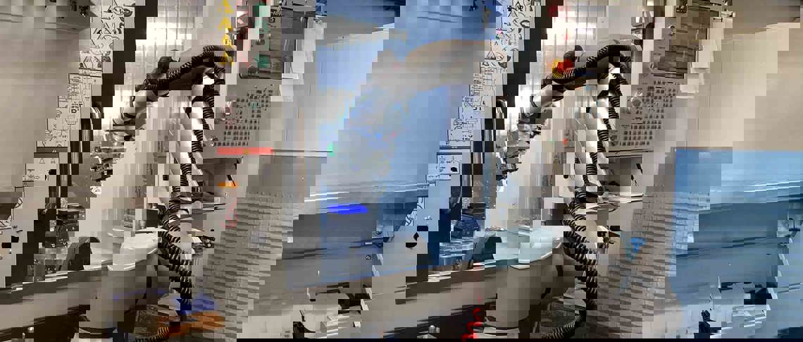 Robotarm sætter plastdel ind i en cnc-fræser