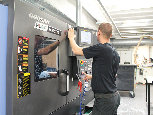 Mechanic adjusting CNC lathe at Induflex's production
