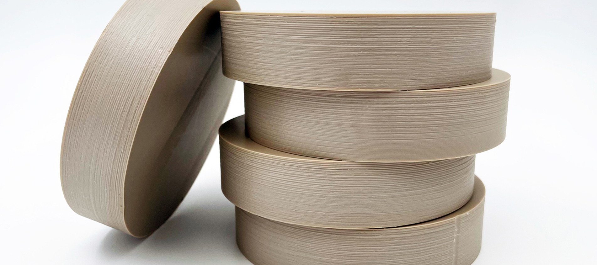 Five round pieces of brown PEEK plastics on a white background