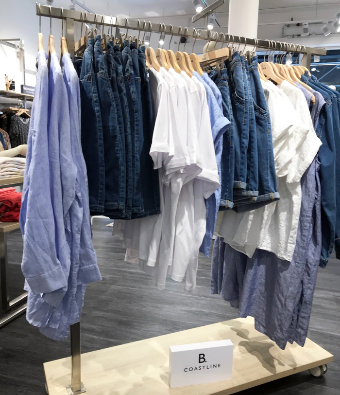 Logoskilt i hvid akryl med sort logoprint udstilles i tøjbutik