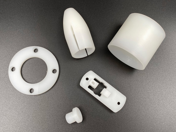 Fem maskindele i naturfarvet PVDF på sort baggrund