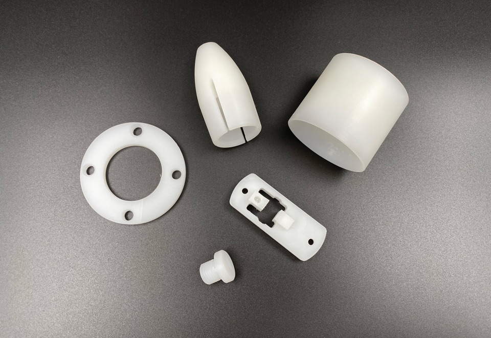 Fem maskindele i naturfarvet PVDF på sort baggrund