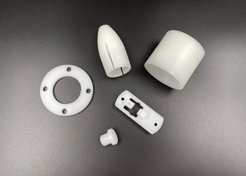 Fem maskindele i naturfarvet PVDF på sort baggrund