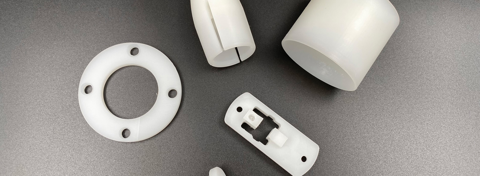 Fem maskindele i naturfarvet PVDF på sort baggrund