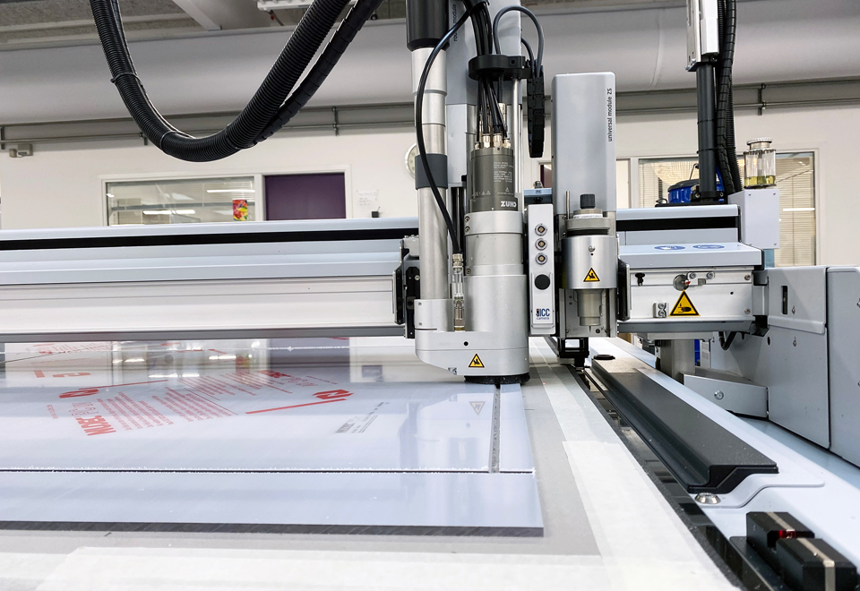 Cutting plotter cutting squares in a sheet of polycarbonate