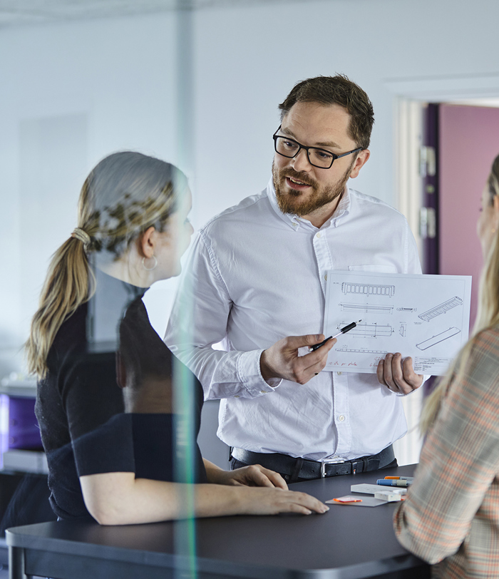 Sales Manager from Induflex shows a technical drawing to two colleagues