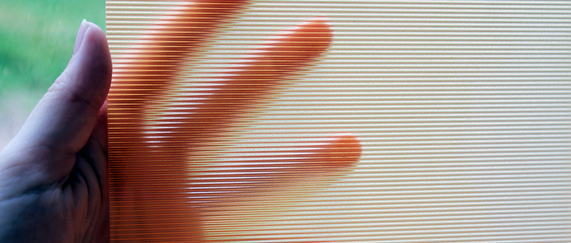 A hand holds a piece of clear ribbed acrylic
