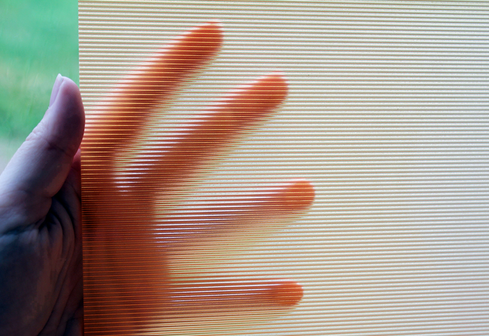 Hånd som holder et stykke gennemsigtigt akryl med riller