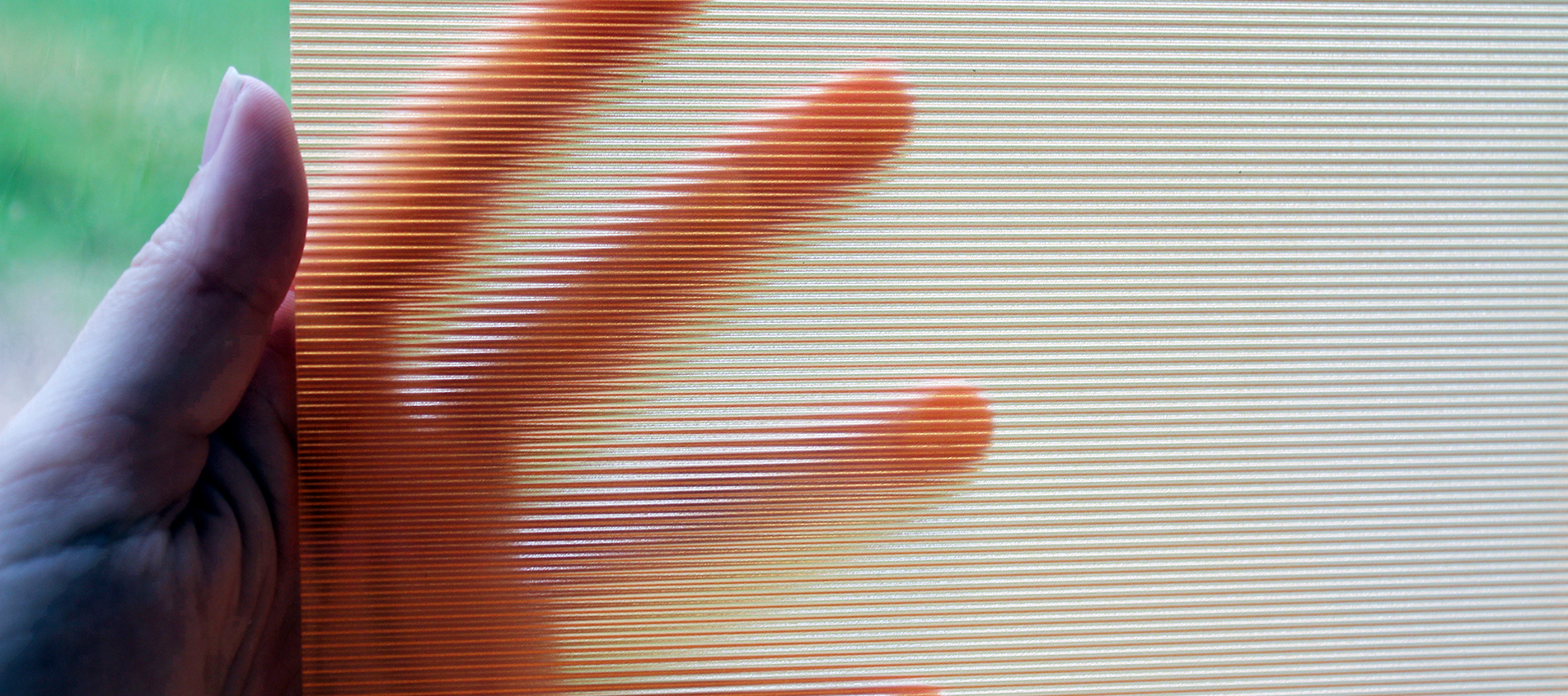 A hand holds a piece of clear ribbed acrylic