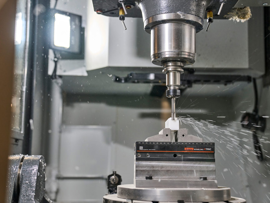 En hvid maskindel i plast fræses ud i en fem-akset fræser.