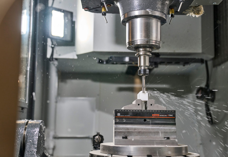 En hvid maskindel i plast fræses ud i en fem-akset fræser.