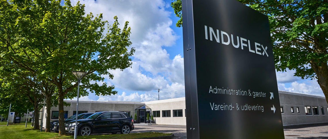 Induflex’ bygning med et sort skilt foran med logo.