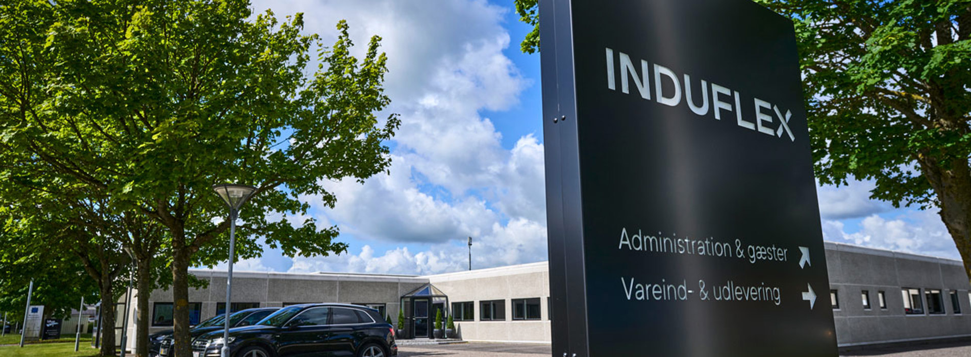 Induflex’ bygning med et sort skilt foran med logo.
