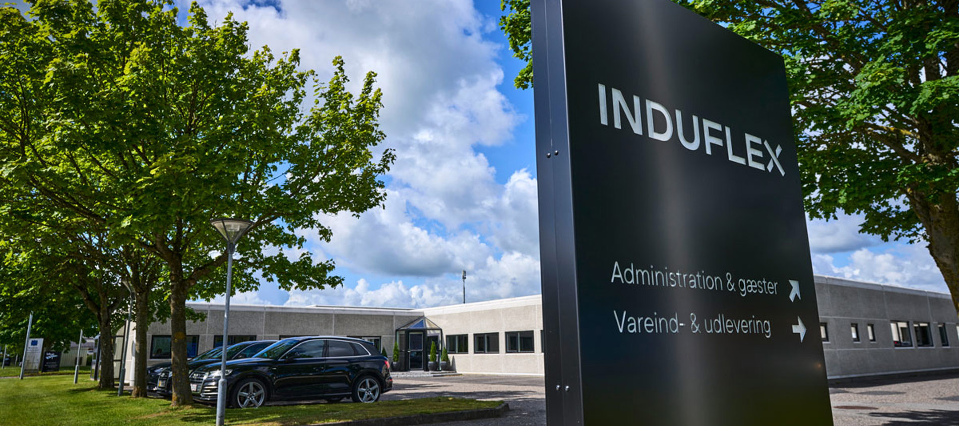 Induflex’ bygning med et sort skilt foran med logo.