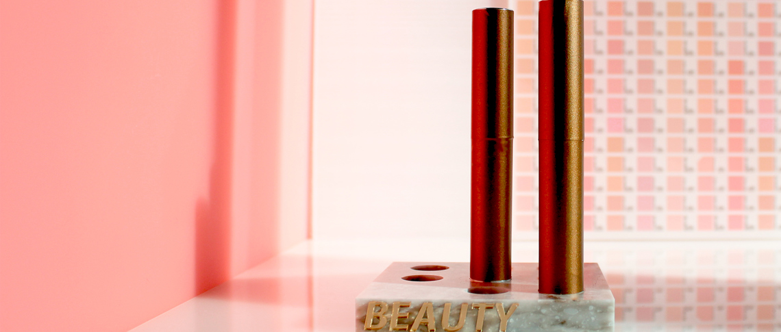 Make-up display in corian with 3D letters in gold mirrored acrylic
