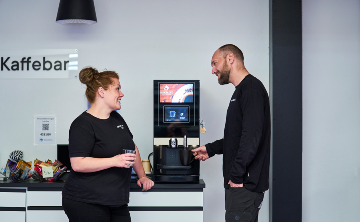 Kolleger snakker om dagen ved kaffemaskinen.
