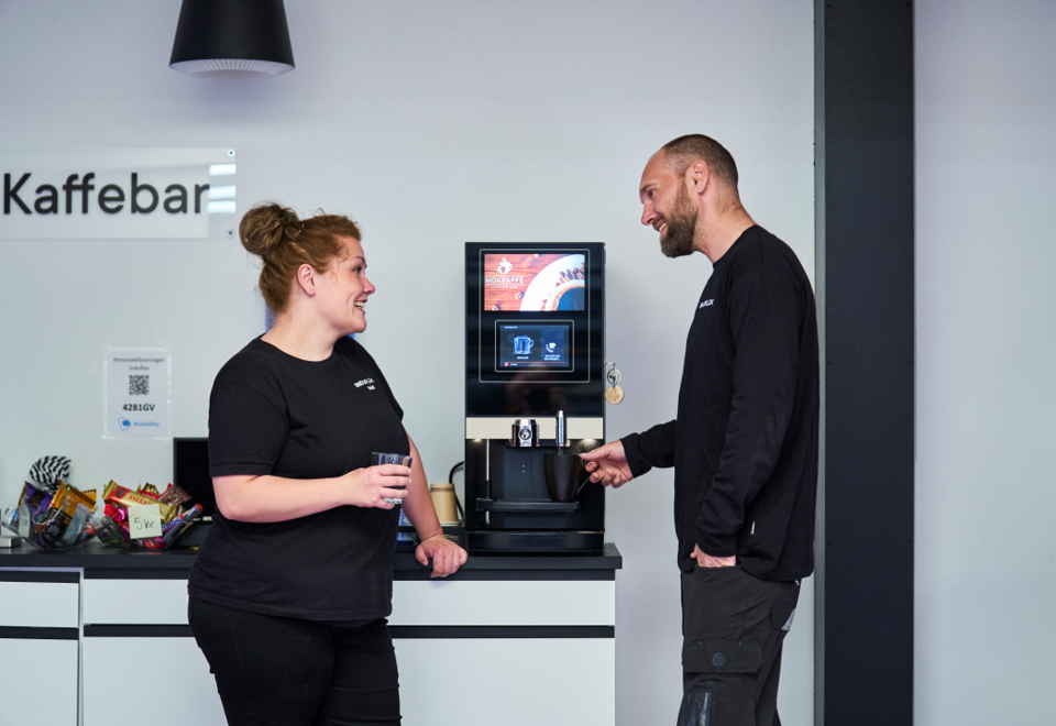 Kolleger snakker om dagen ved kaffemaskinen.