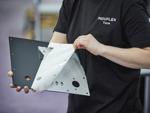 Assembly worker dismounts foil on a black sheet of plastic