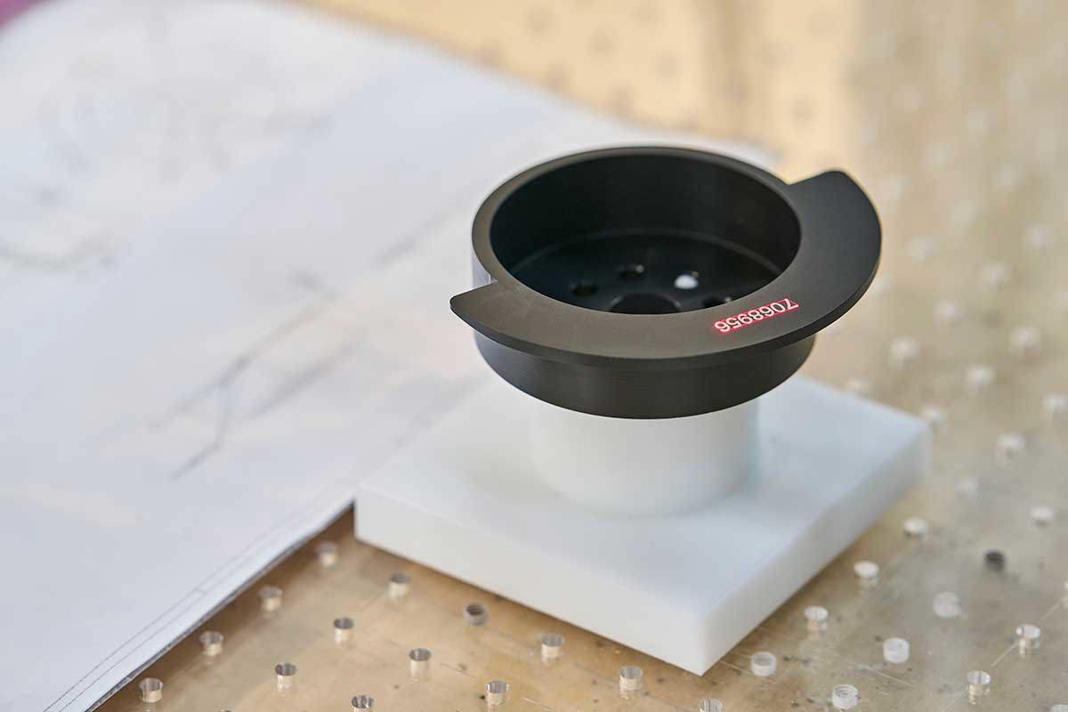 Sort drejet maskindel med lasergraverede tal på sig.