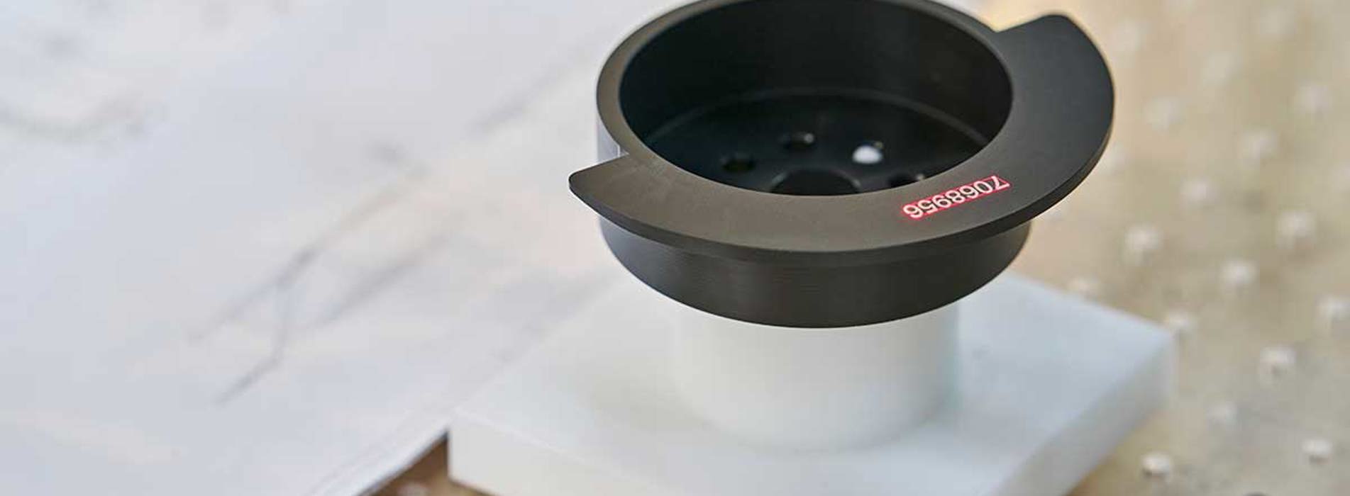 Sort drejet maskindel med lasergraverede tal på sig.