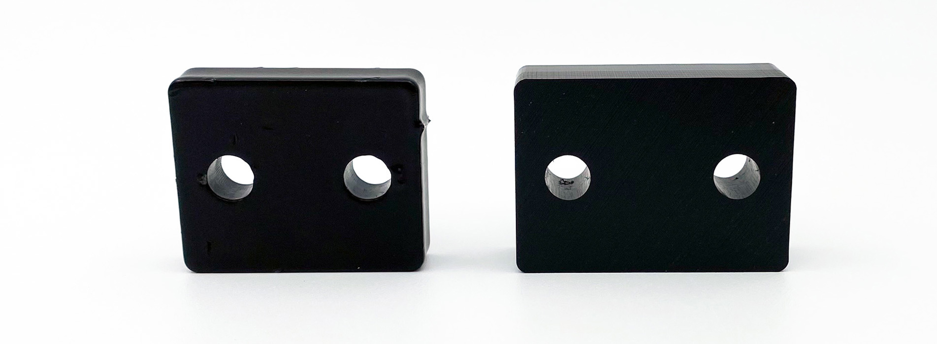 To identiske afstanddstykker, hvoraf det ene er lavet af sort plast og det andet af lakeret metal