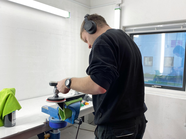 A production worker is polishing a piece of black acryllic