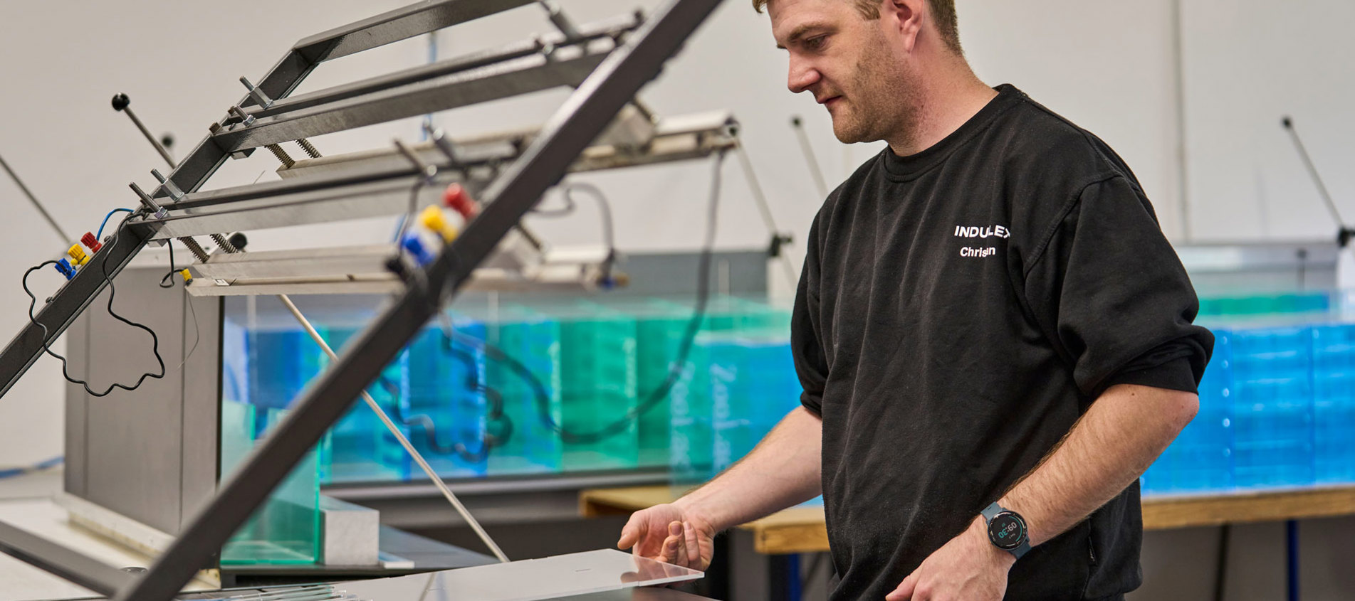 En medarbejder justerer et akrylstykke som ligger på et varmbukke-bord.