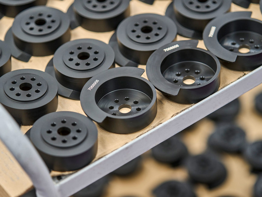A table full of black machine parts with engraved numbers.