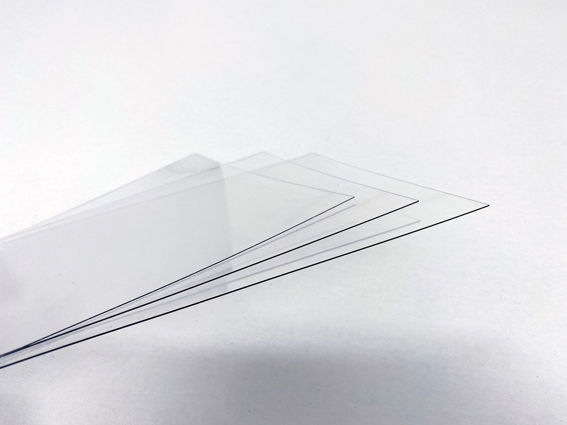 Tre tynde plader af gennemsigtig PET plast på en hvid baggrund