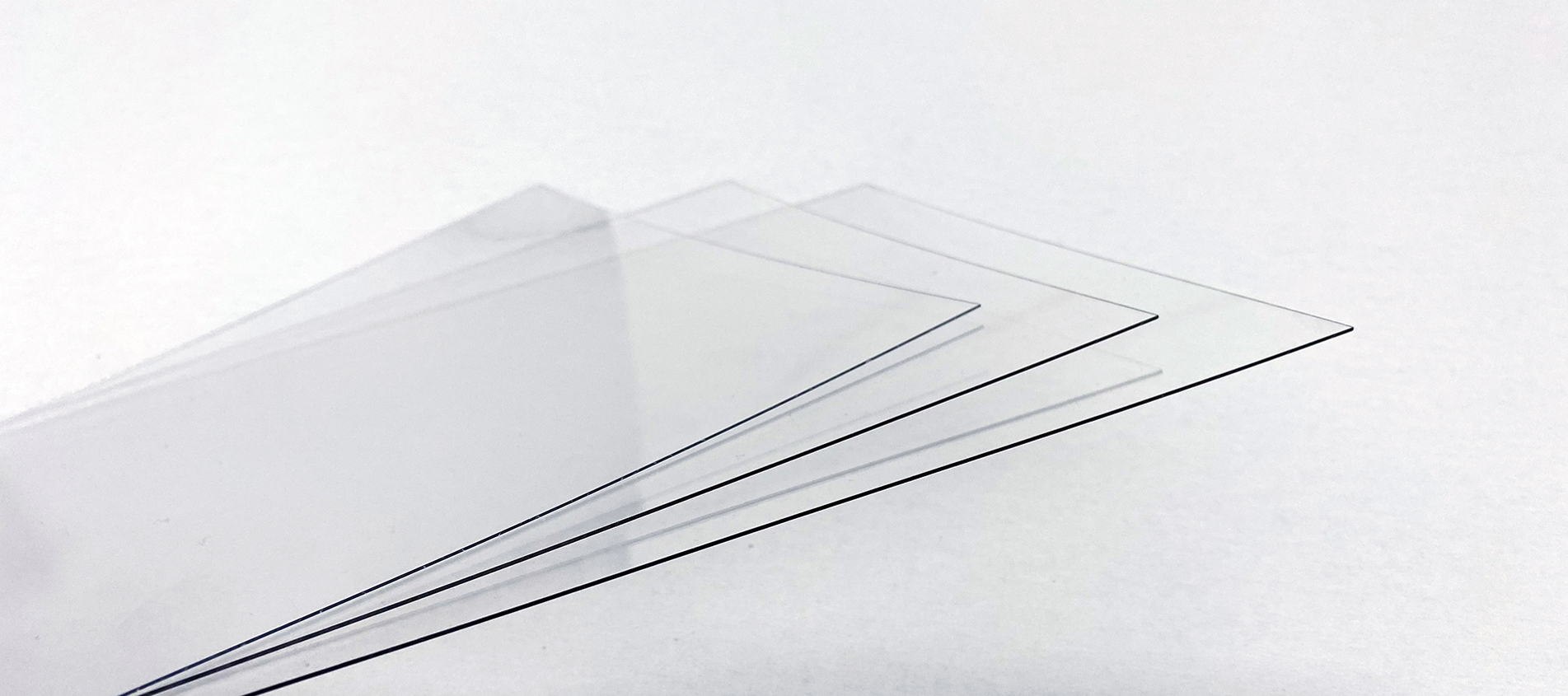 Three thin sheets of clear PET plastic on a white background