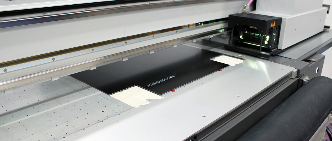 Digital printer in Induflex's production printing a white logo on black acrylic