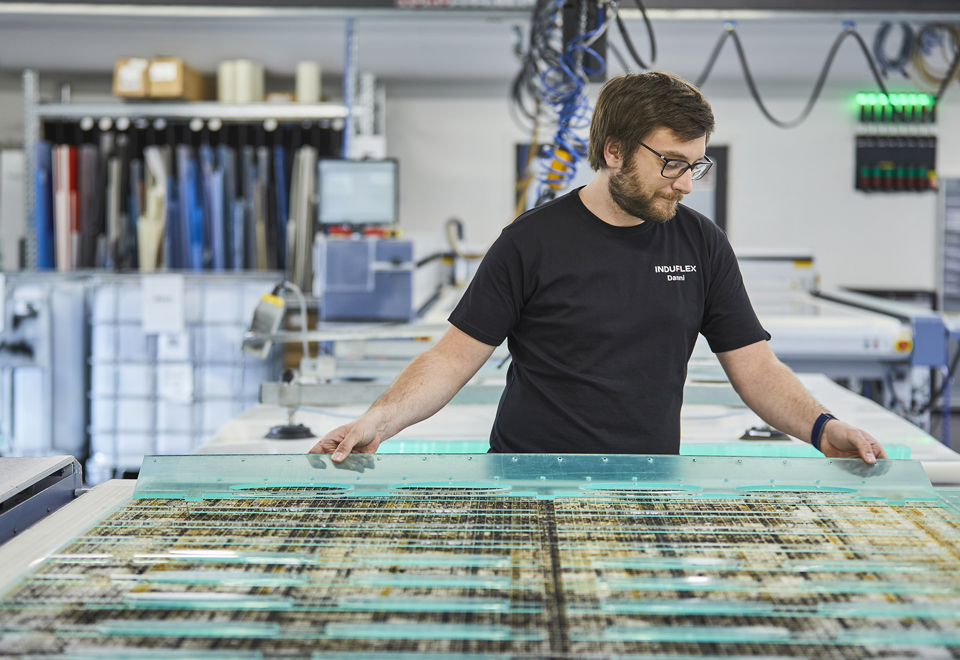 Industry technician changes sheet on a laser cutter with clear acrylic