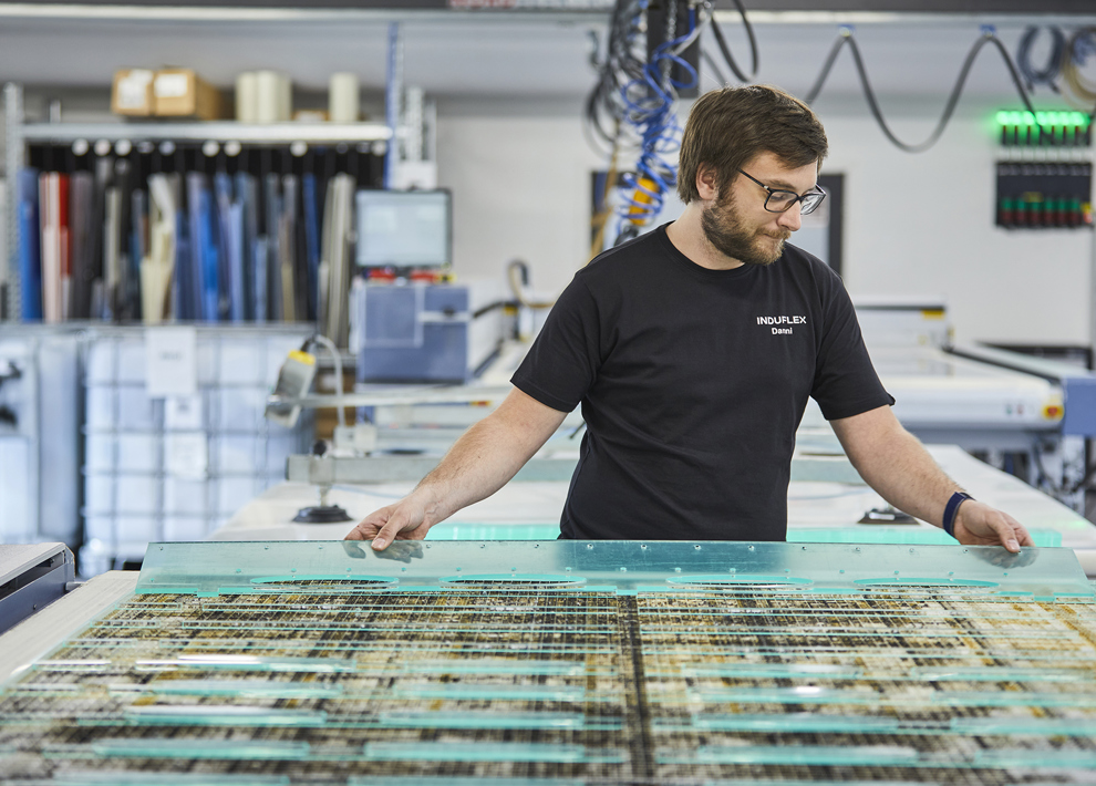 Industritekniker skifter plade på en laserskærer med klar akryl