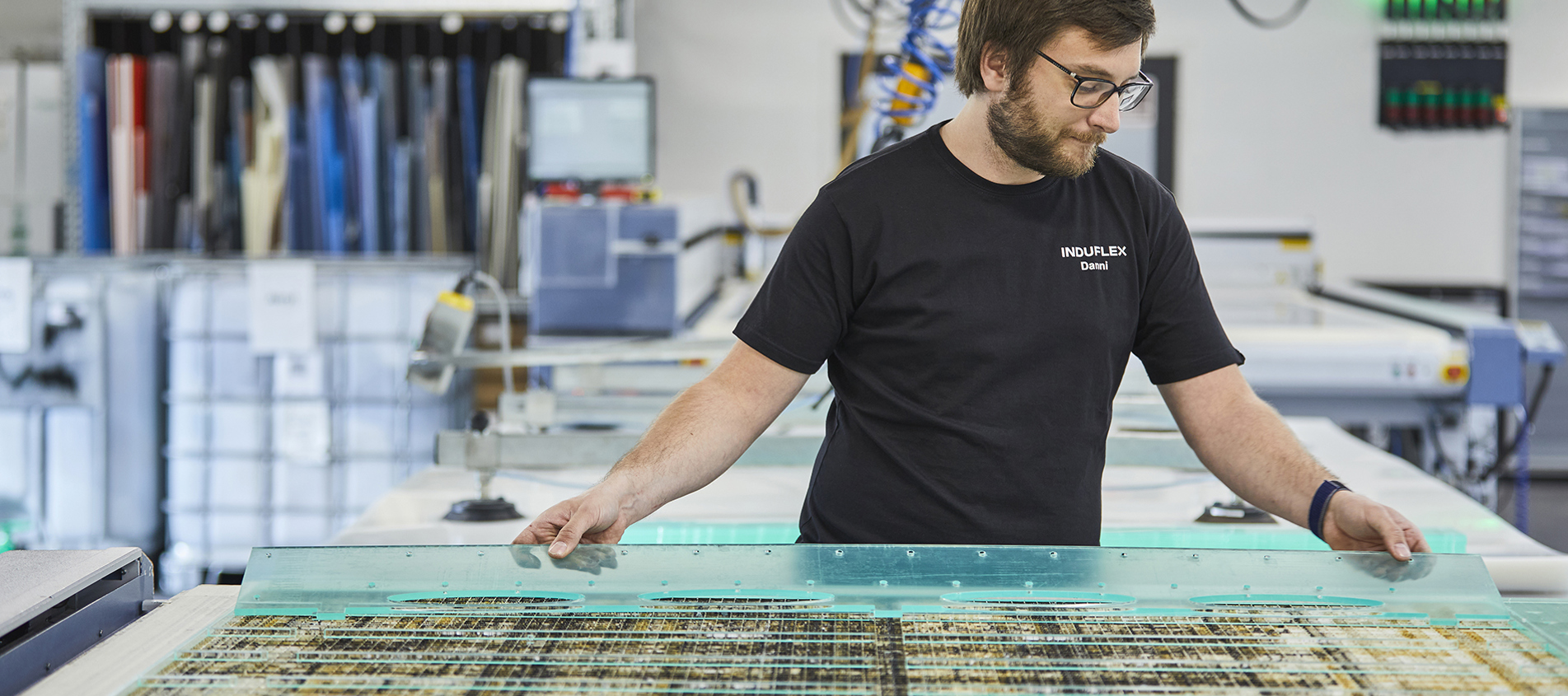 Industritekniker skifter plade på en laserskærer med klar akryl