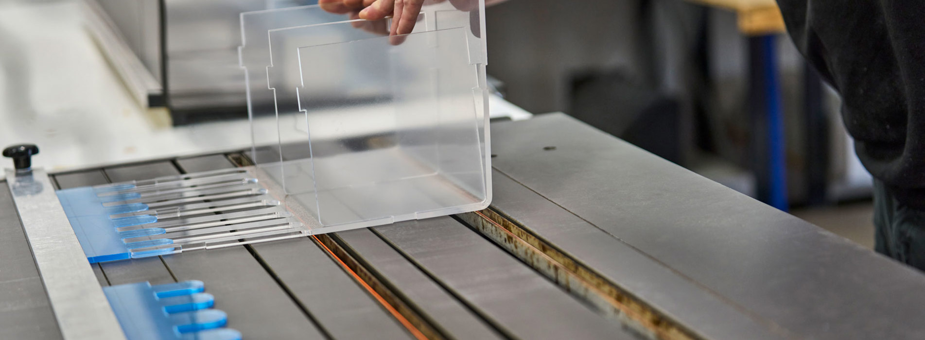 En medarbejder justerer et display i akryl, som ligger på et varmbukke-bord.
