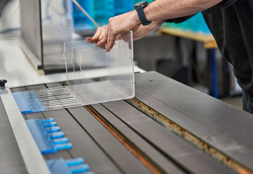 An employee adjusts a display of acrylic that lies on a heat-bending table.