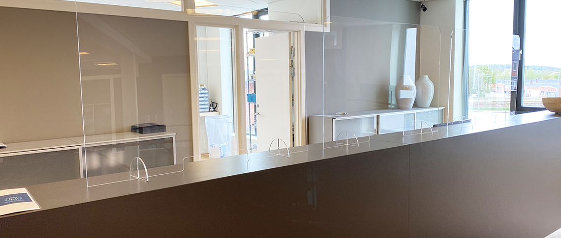 Partition screens in clear plastic can protect customers and employees by resting on a counter in a reception