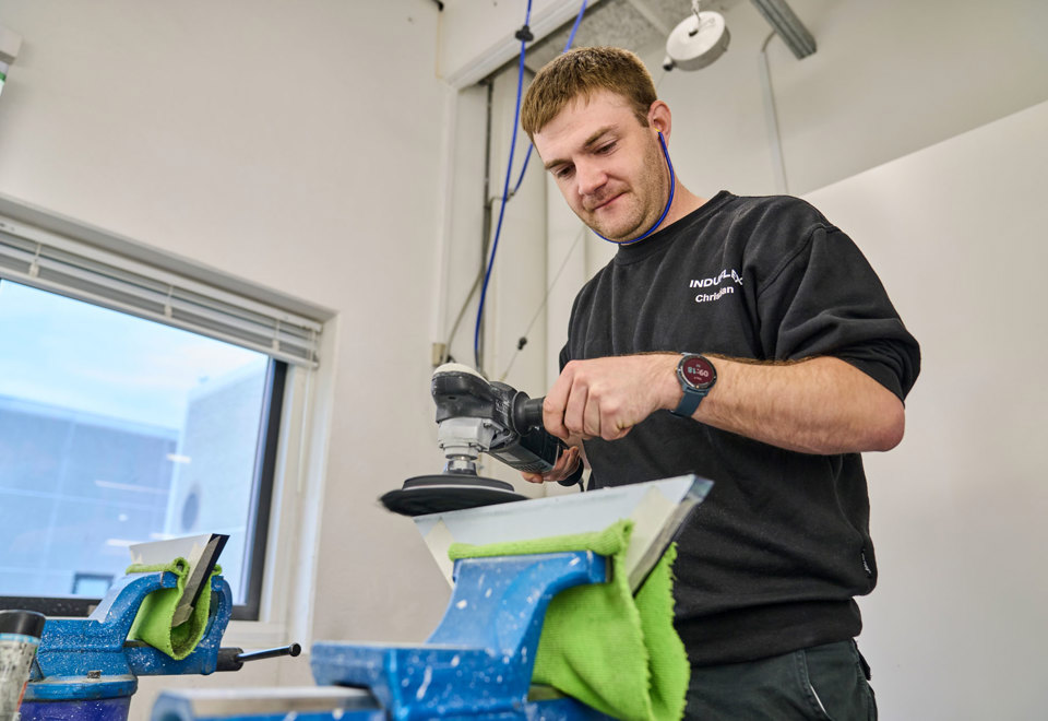 An employee polishes a piece of acrylic manually with a polishing machine.