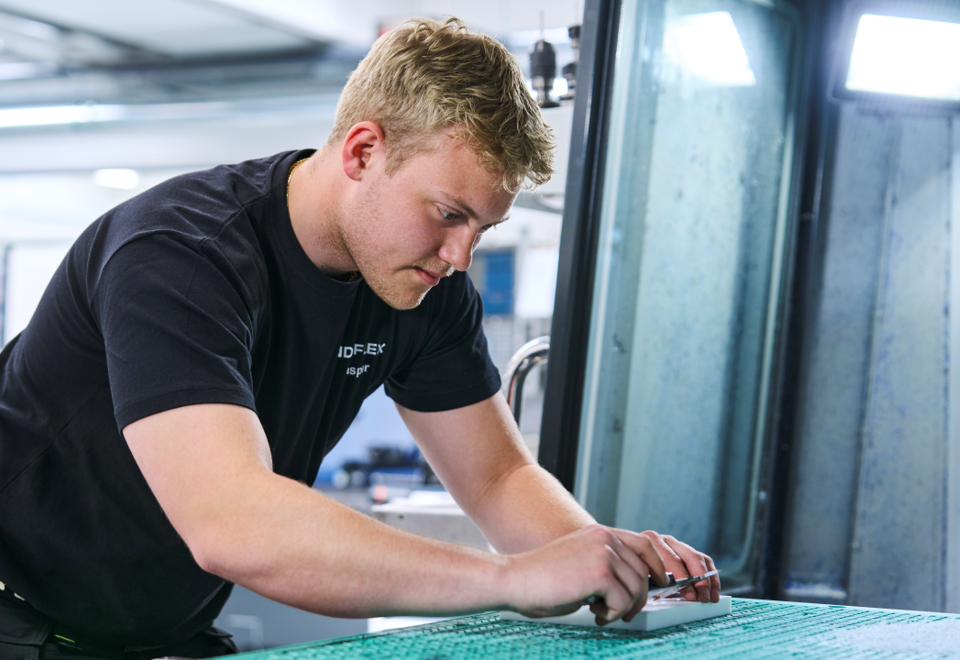Industrial technician checks measurements on plastic component.