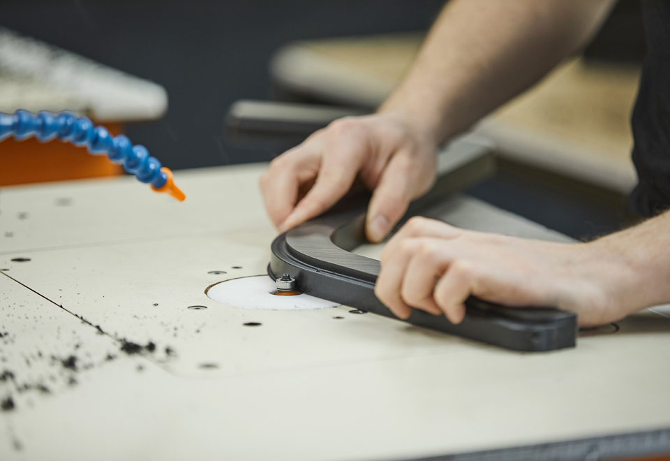 Produktionsmedarbejder hos Induflex afgrater et plastemne i sort POM