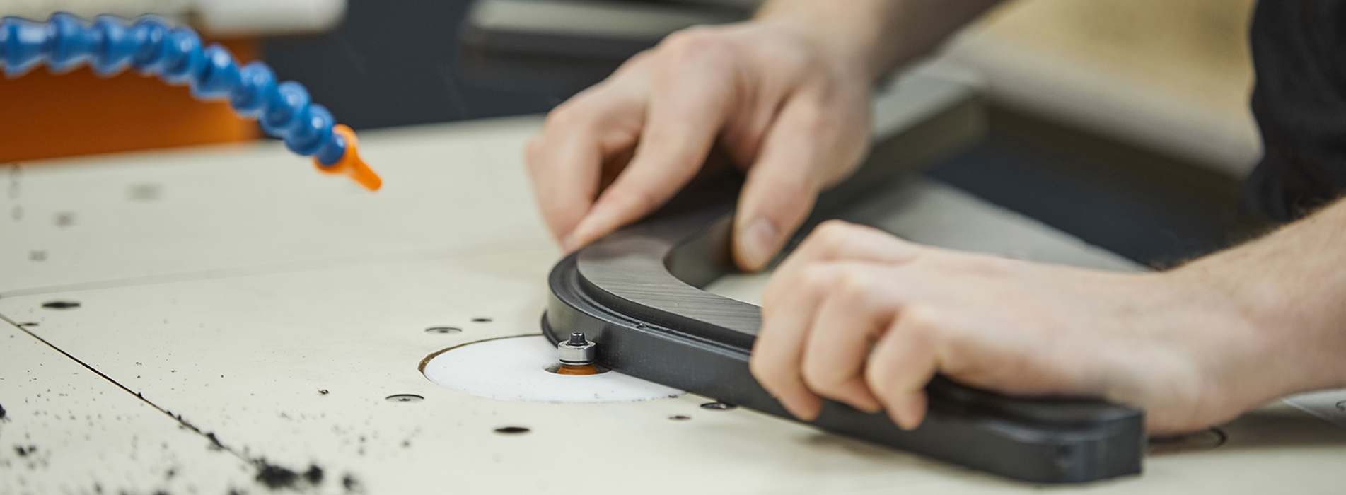 Produktionsmedarbejder hos Induflex afgrater et plastemne i sort POM