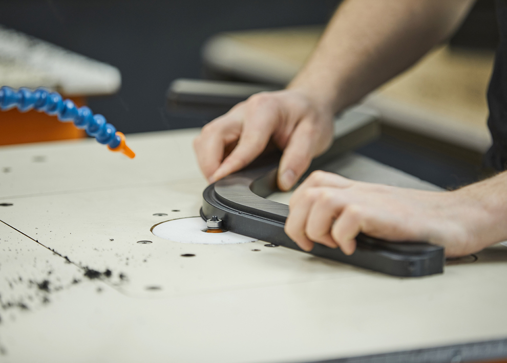 Production employee at Induflex deburring a plastic part in black POM