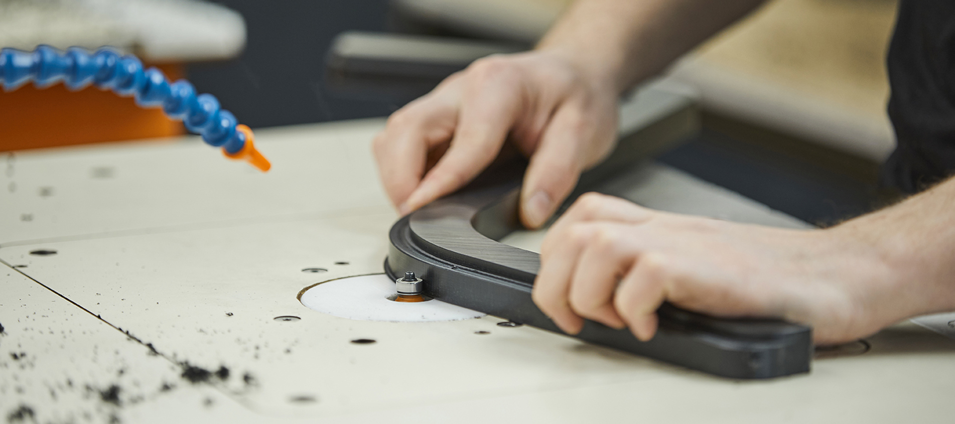 Produktionsmedarbejder hos Induflex afgrater et plastemne i sort POM