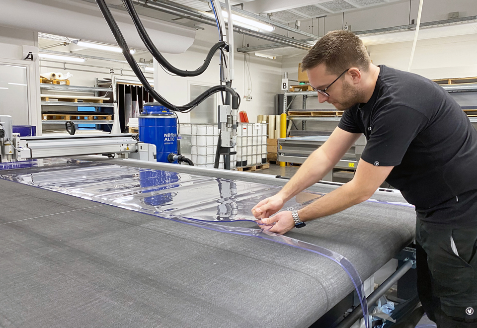 A production worker is controlling a cut piece of PVC on a cutting plotter