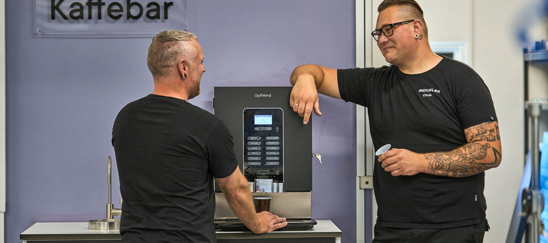 To industriteknikere holder pause ved en kaffebar i værkstedet. 