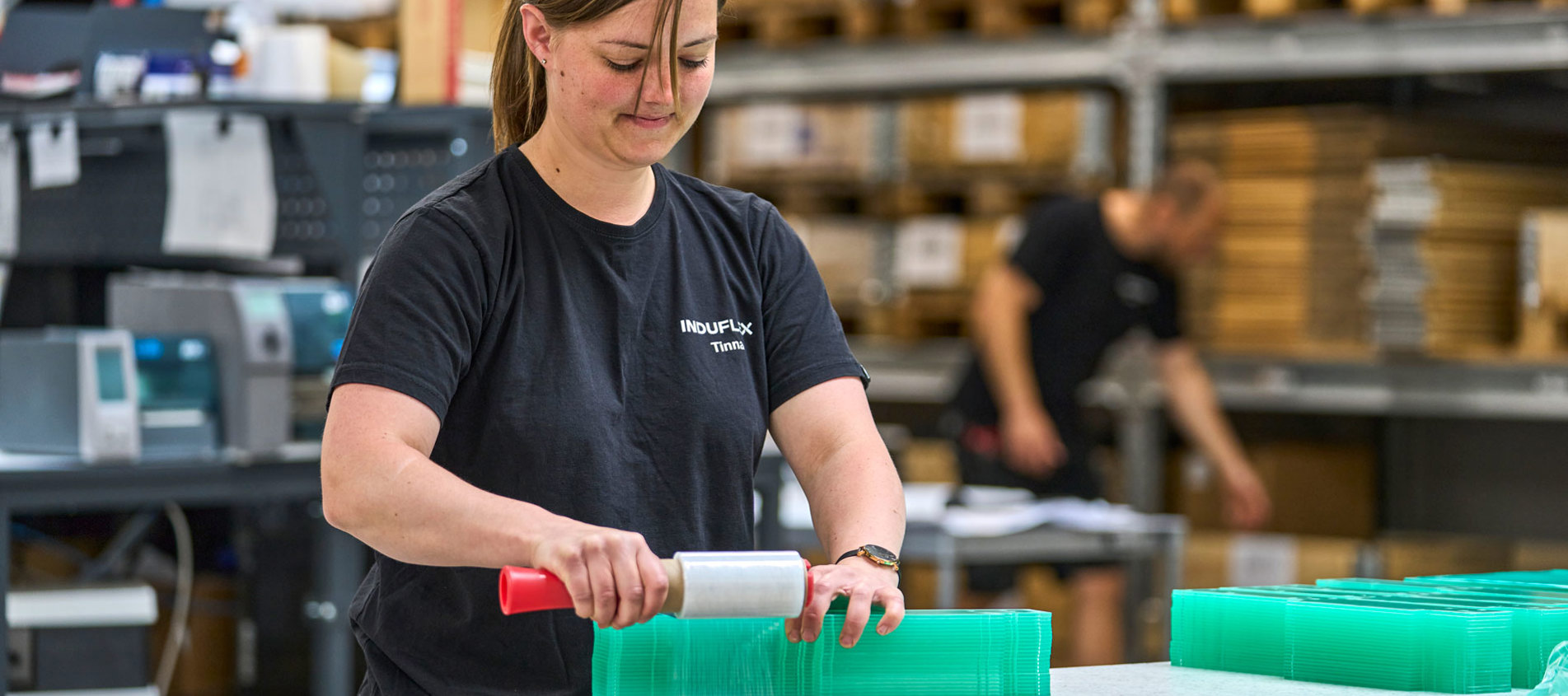 En lagermedarbejder pakker gennemsigtige plastdele sammen i forsendelsen. 