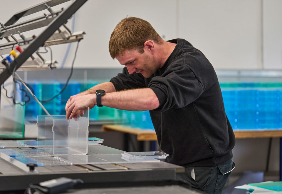 A worker heat bends an acrylic display.