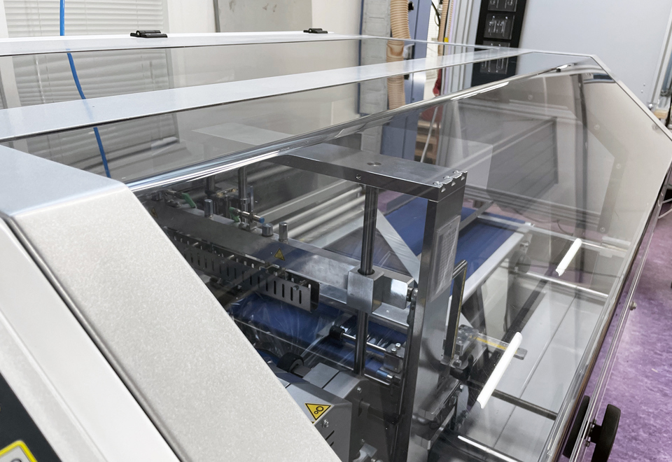 En gennemsigtig, bukket maskinafskærmning sidder på en maskine.