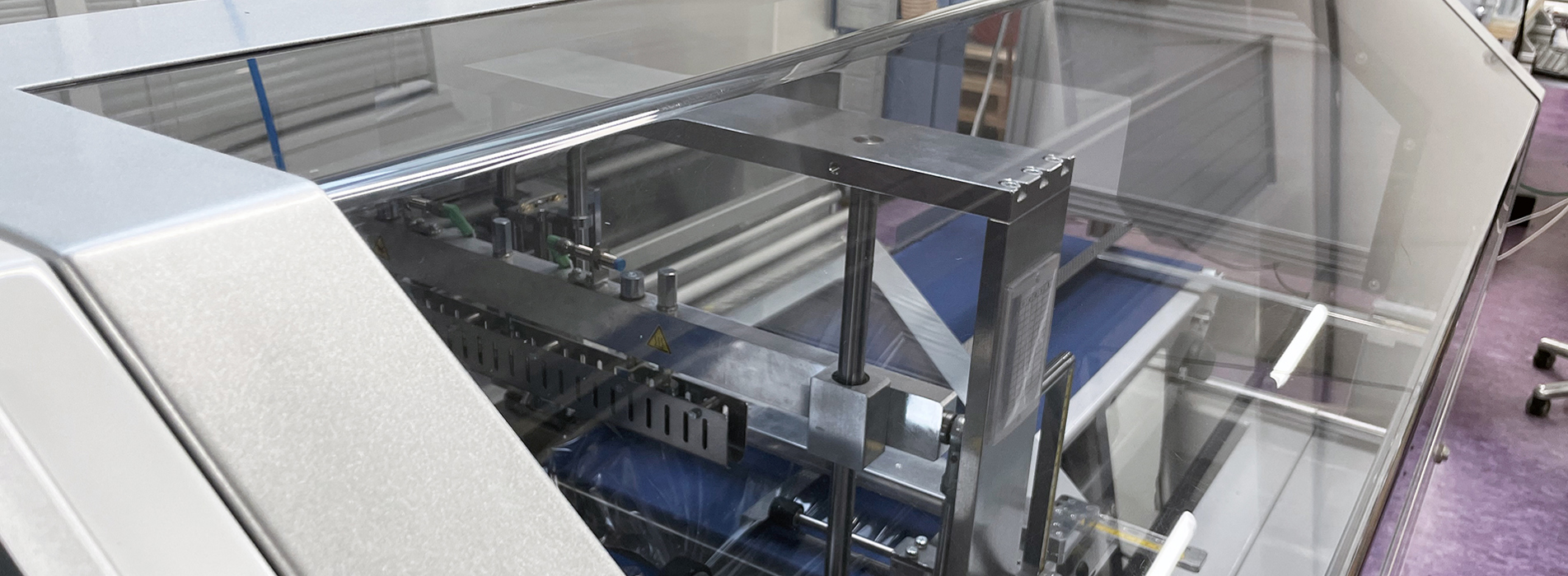 En gennemsigtig, bukket maskinafskærmning sidder på en maskine.